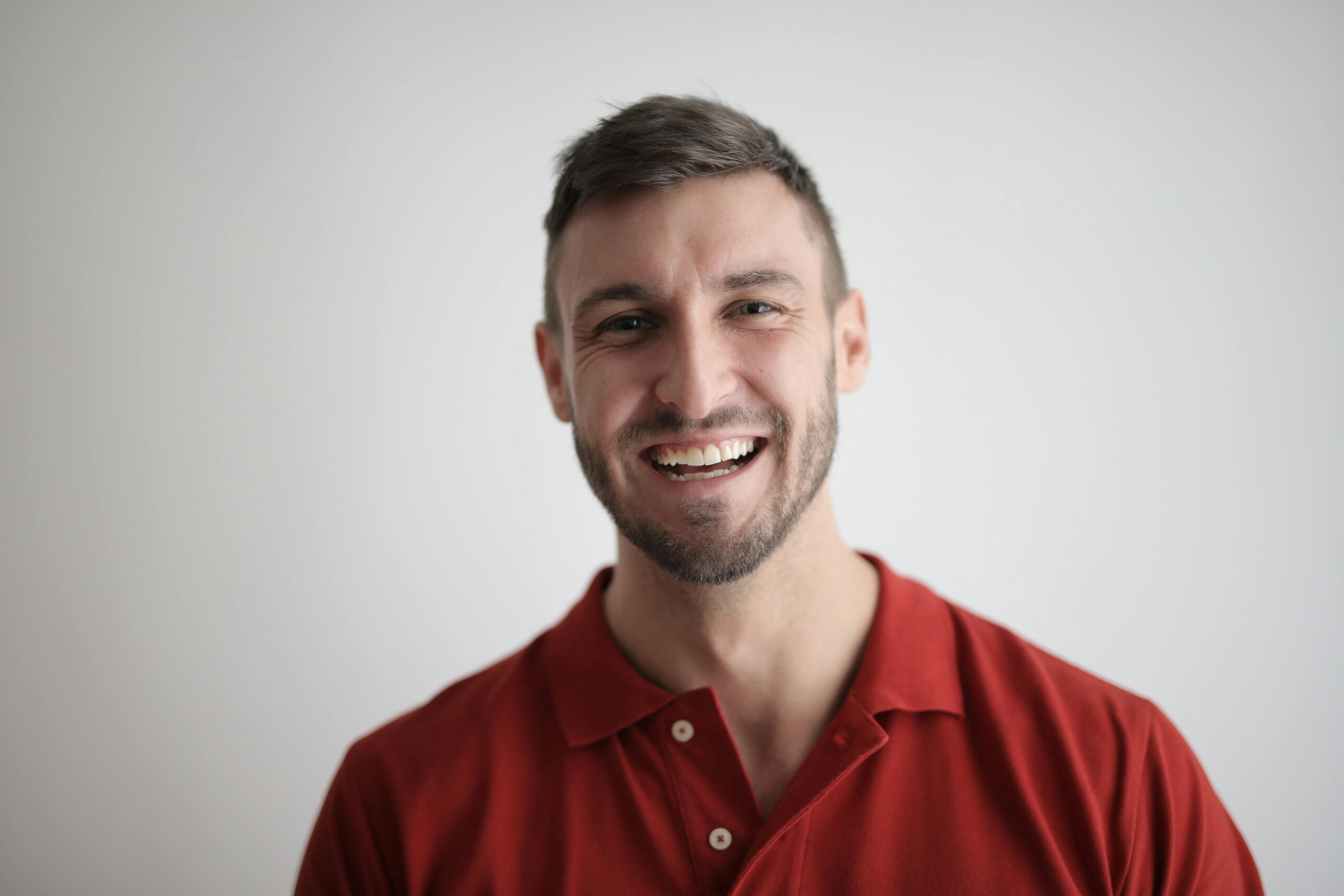 A cheerful man smiling broadly against a plain white background.